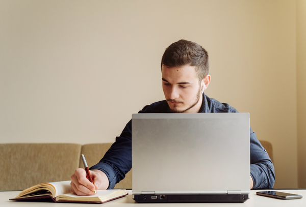 A imagem contém um jovem estudante com seu notebook, mostrando como é essencial saber como organizar os estudos na faculdade.