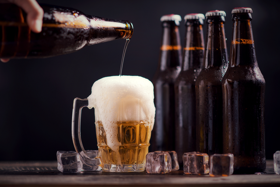 Imagem de várias garrafas de cerveja e uma sendo servida em um copo de choop. 